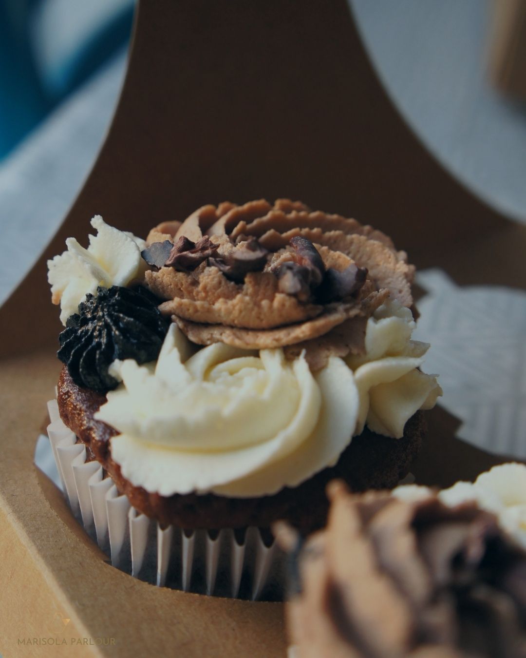 Delicate cupcake with white frosting and chocolate decorations on a blurred background