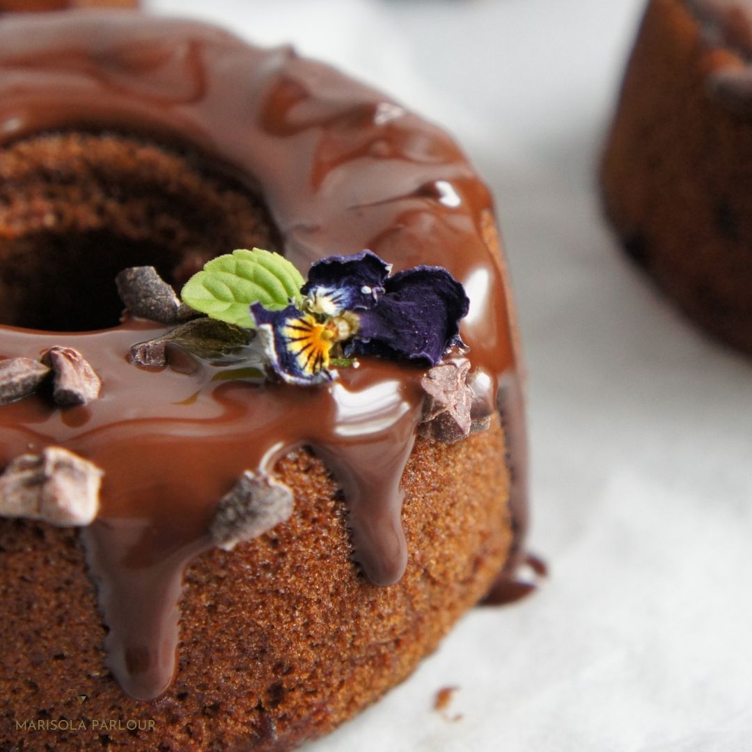 Vegan Gluten-Free Bundt chocolate Bundt cake decorated with a chocolate drip and edible viola and mint leaf