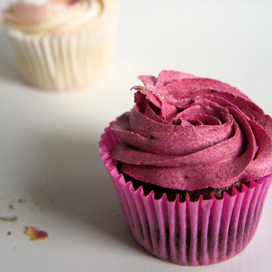 Gluten-free vegan cupcake with pink frosting on a white surface