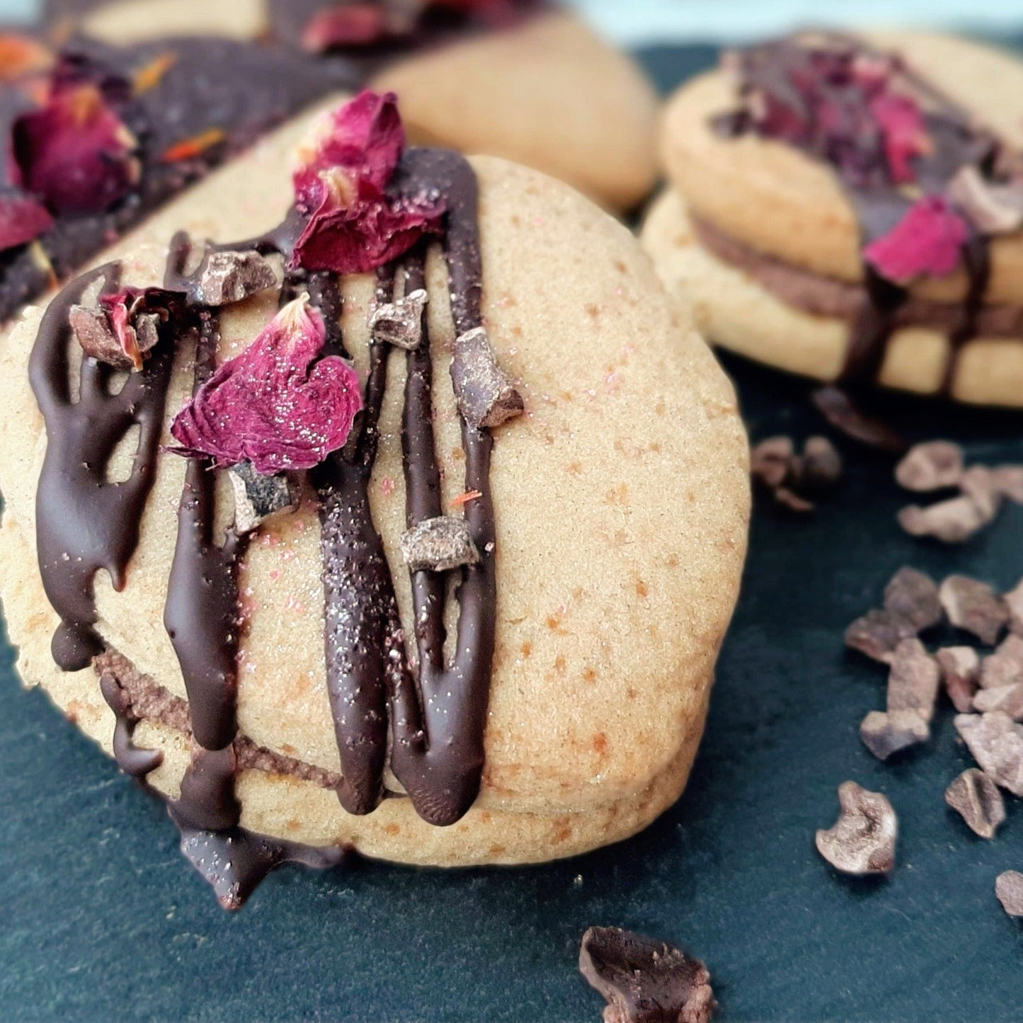 Gluten-free Cookies with chocolate drizzle and dried berries on a dark surface