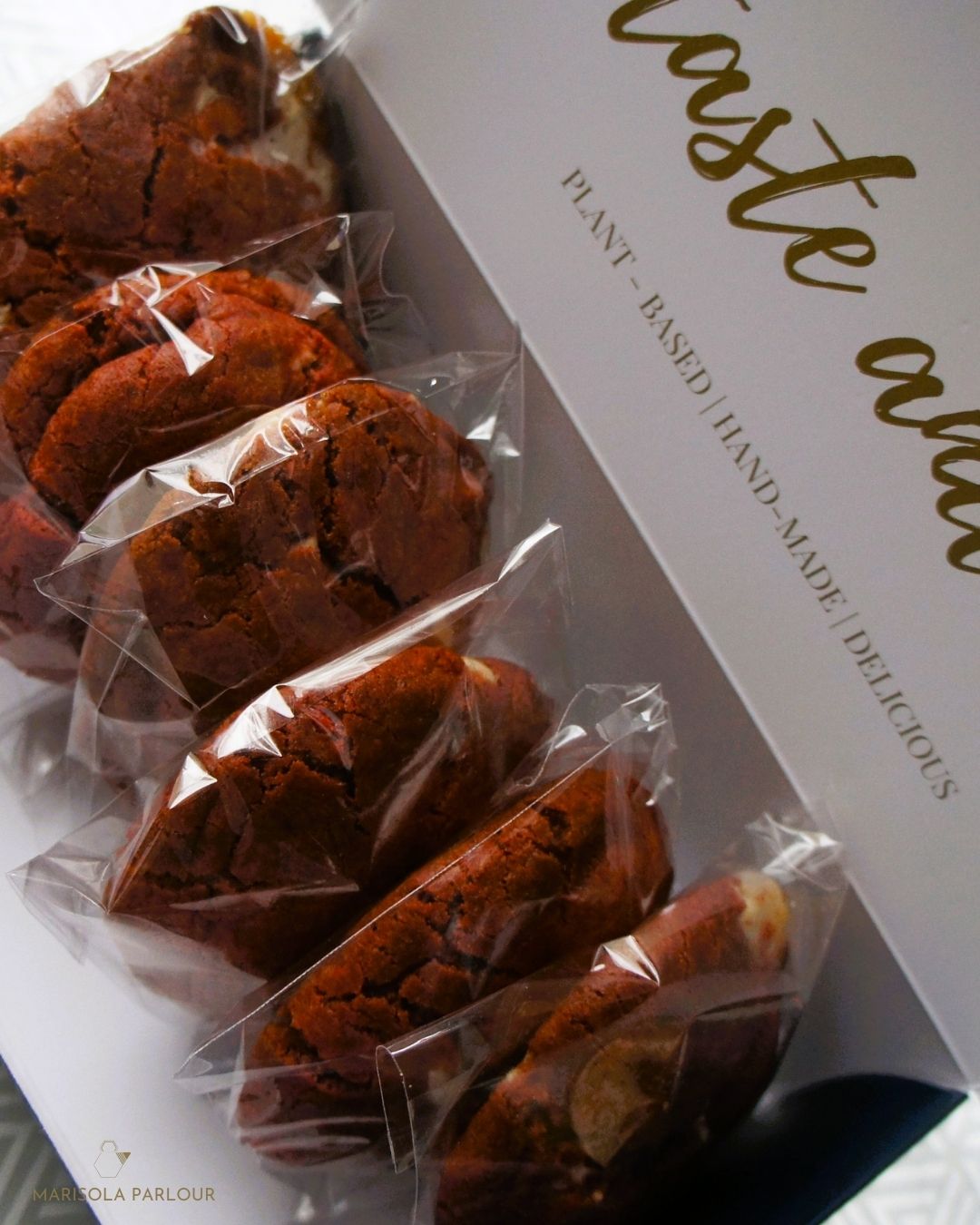 Packaged cookies in clear plastic on a white box with gold text.