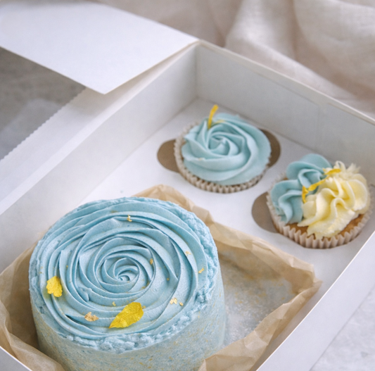 Plant-based gluten-free Easter bento cake with two matching cupcakes in blue speckled buttercream, presented in a gift box.