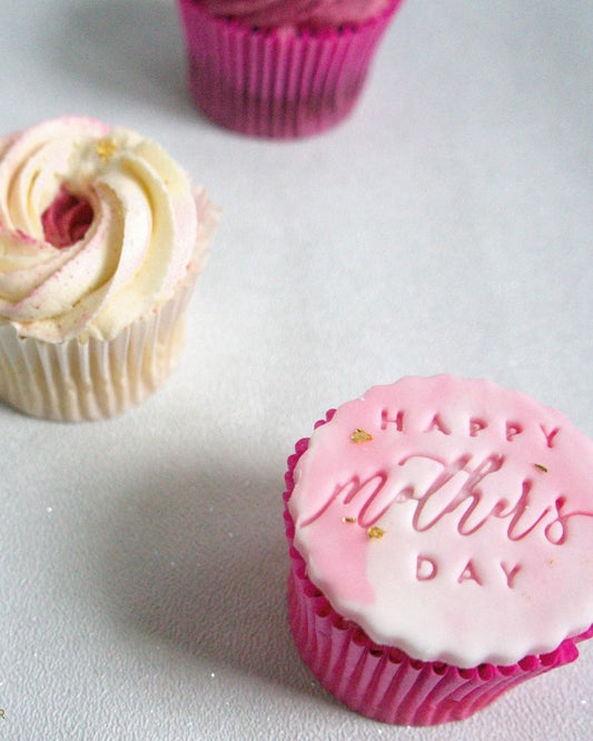 Cupcake with pink frosting and 'Happy Mother's Day' message on a light gray background